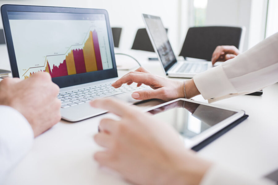 Cropped shot of businessmen and woman looking at laptop charts in office